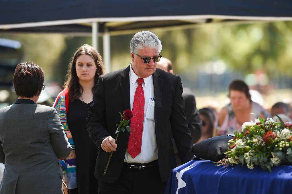 Cherished: Rob Moran goes to place a rose on his wife's coffin as his and Detective Senior Constable Marg Saunders' daughter Majella Moran follows behind. Picture: MARK JESSER