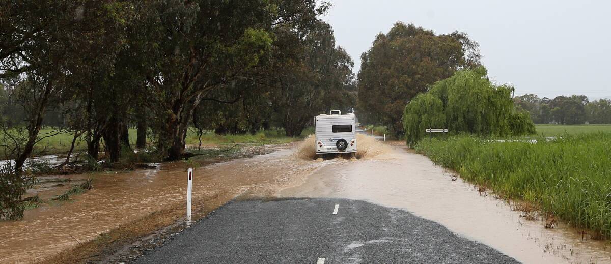 Taking on the water: A caravanner drives through flood waters covering the Jingellic-Holbrook Road on Friday. Picture: JAMES WILTSHIRE