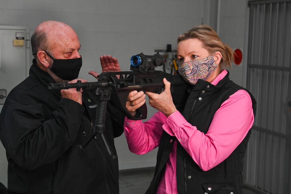 Getting a sighter: InVeris Training Solutions key account manager Leon Helmrich makes a point to Sussan Ley as she positions a modified EF88 rifle used as part of its simulated training for weapons. Picture: MARK JESSER