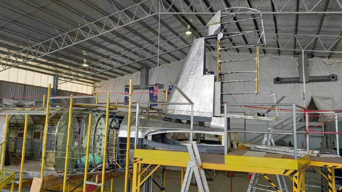 Taking shape: The rudder is added to the fin as part of the reassembling of the plane's empennage. Picture: RUSS JACOB