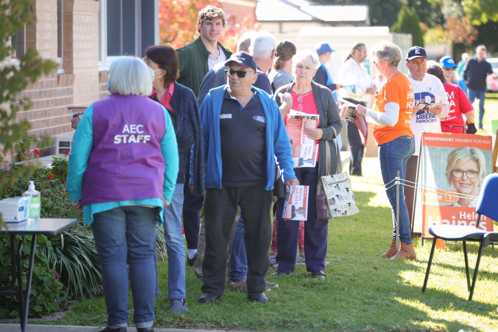 Democracy in action: Voters line up to cast ballots in Wodonga with politicians Helen Haines and Tim Quilty among those handing out flyers. Picture: JAMES WILTSHIRE