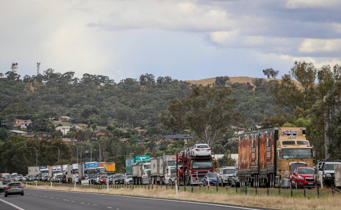 Long lines: Trucks and cars line up to cross into Wodonga at the Hume Freeway checkpoint. Picture: JAMES WILTSHIRE