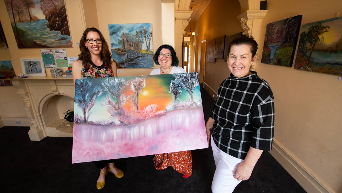 Bright look: Sacha Markham, Melanie Martinelli and Liz Marmo with artworks now gracing the Englehardt Street premises. The oil paintings range in size from A3 to 1.5 metres x 1 metre. Picture: MARK JESSER