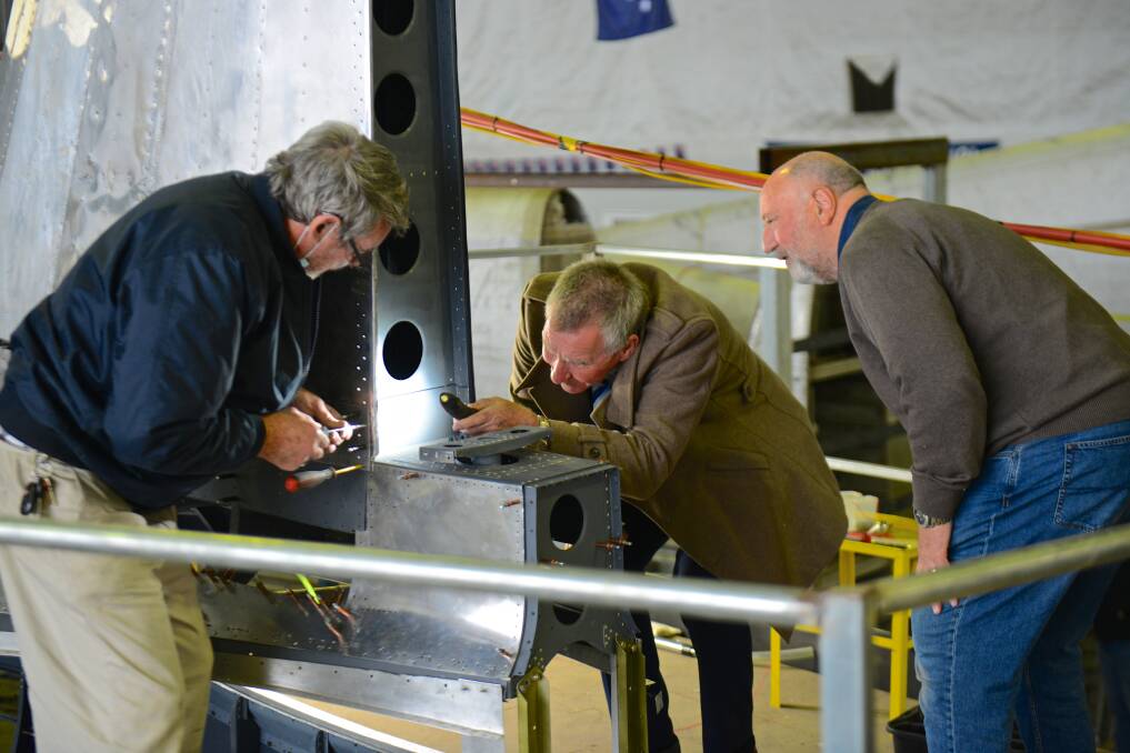 On the job: Albury mayor Kevin Mack and Uiver restorers Russ Jacob and Pieter Mol work on reattaching the tail to the Uiver memorial plane. Picture: IAN COSSOR