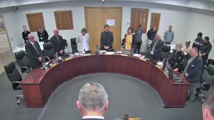 Councillors, staff and members of the gallery at the Federation meeting stand for a minute's silence for Zoe Wilson. Still from live stream.