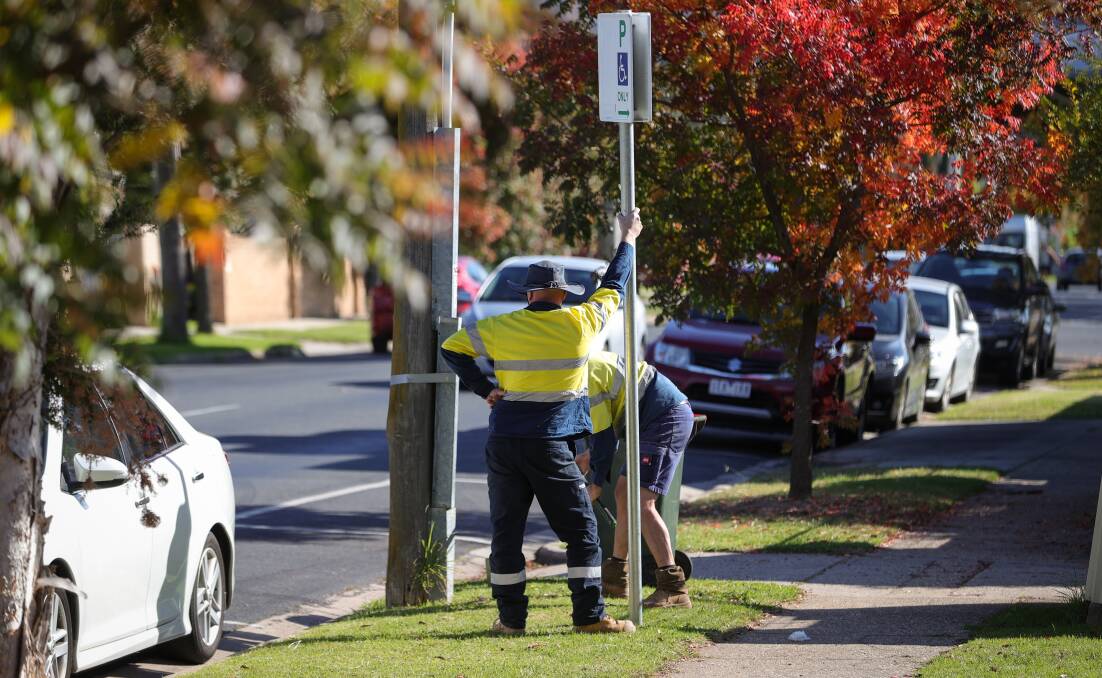 Digging in: Wodonga Council workers install a disabled parking sign in Lawrence Street outside the early voting centre on Monday. Picture: JAMES WILTSHIRE