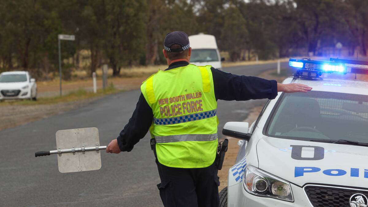 On the job: A NSW policeman stops traffic for drug tests outside the Strawberry Fields festival on Sunday. Roadside testing resulted in 20 drug finds with four charged with drug possession and 19 samples to be tested further. 
