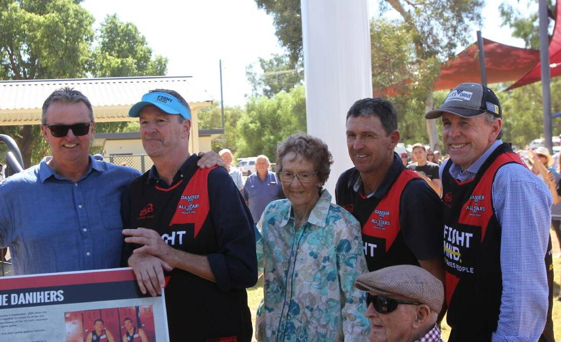 Family affair: Brothers Tony, Neale, Chris and Terry Daniher with their parents Edna and Jim and a plaque that sits below the football and outlines their feats. 