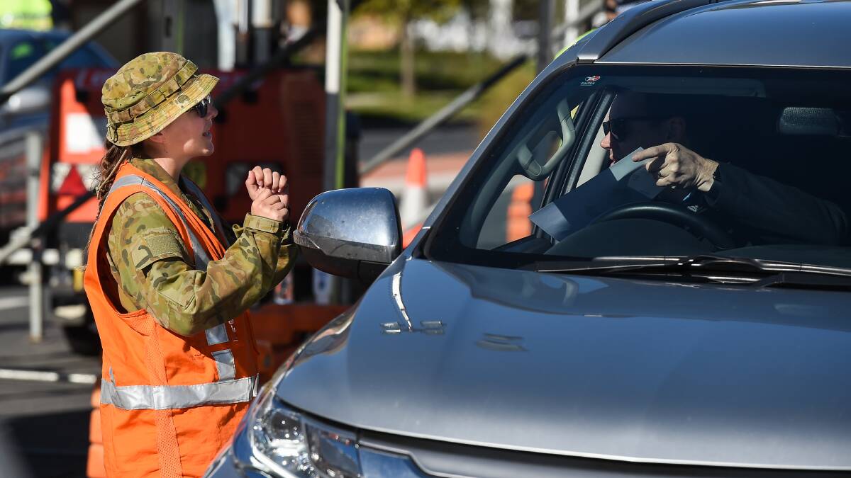 On duty: A soldier checks a motorist's details at Wodonga Place in Albury on Friday. She is among a contingent staying at the Mantra hotel in Albury while part of the border crossing operation. Picture: MARK JESSER