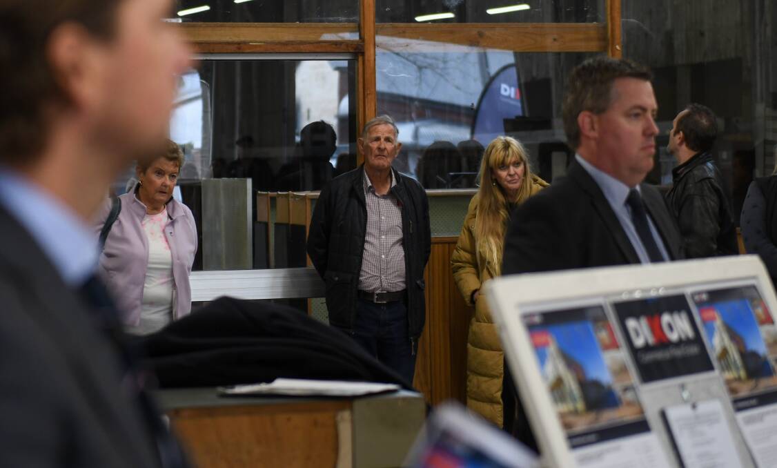 Doug Dyde leans against a wall and watches keenly as his former store is auctioned. His wife Colleen is to the left of the image. Picture by Tara Trewhella