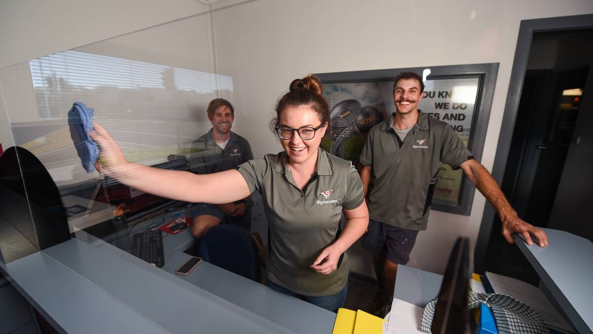 Perspex peering: Signarama staff Emma Gladwin with Jarryd Weeding and Jayden McCabe and one of the screens designed to ease concern over coronavirus spread. Picture: MARK JESSER