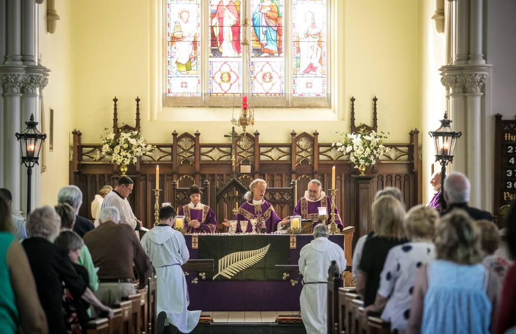 Long white cloud lingering: Father Peter MacLeod-Miller conducts his service at St Matthew's Anglican Church on Sunday. A banner bearing a silver fern adorned the altar along with 50 candles to mark the terrorist massacre at New Zealand mosques. Picture: JAMES WILTSHIRE