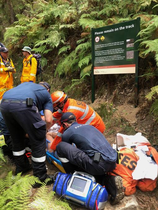 Grim situation: The man who fell down the Eurobin Falls is stabilised near a sign which warns bushwalkers to remain on the track and not risk their life.