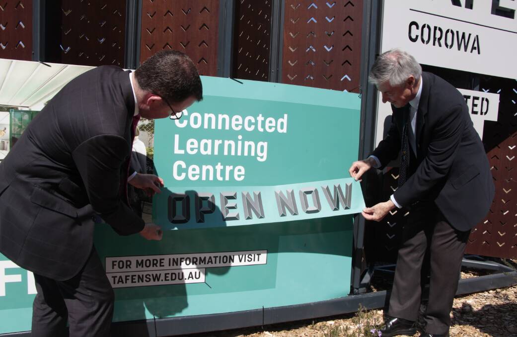 Now operating: Adam Marshall and Greg Aplin place and "open now" sticker over the sign outside Corowa TAFE's Connected Learning Centre.