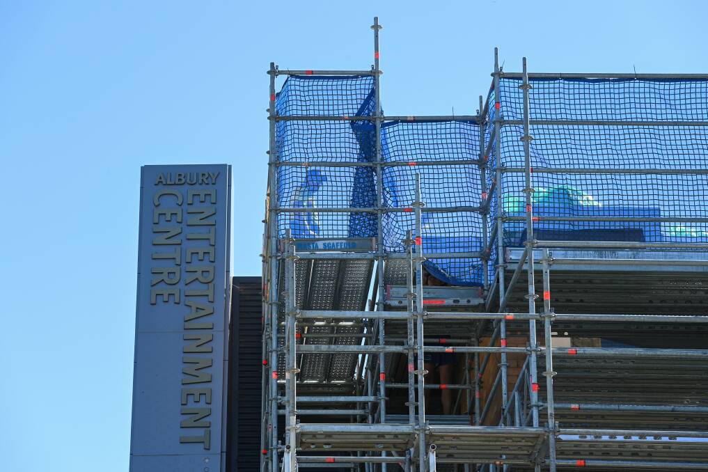 Up in the air: A worker negotiates his way around the roof of the Albury Entertainment Centre.