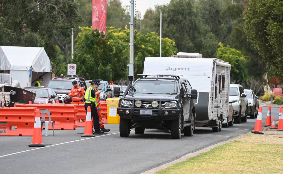 Negotiating the checkpoint: A holidaymaker returns to Victoria through Wodonga's Lincoln Causeway inspection station with their caravan on Friday morning Picture: MARK JESSER