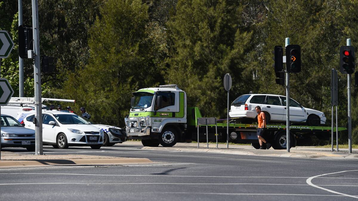 Aftermath: A tow truck driver checks the tethering for the Mitsubishi Lancer stationwagon linked to a wanted man who fled after the car crashed into two others along the southern end of Wodonga's Lincoln Causeway on Monday afternoon. Picture: MARK JESSER