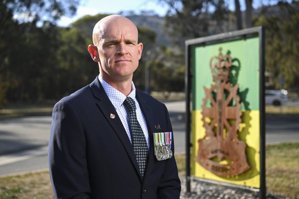 Jesse Sutherland in front of the North Bandiana base entry sign that displays the insignia of the Army School of Electrical Mechanical Engineering with which he has had a long connection. Picture by Mark Jesser