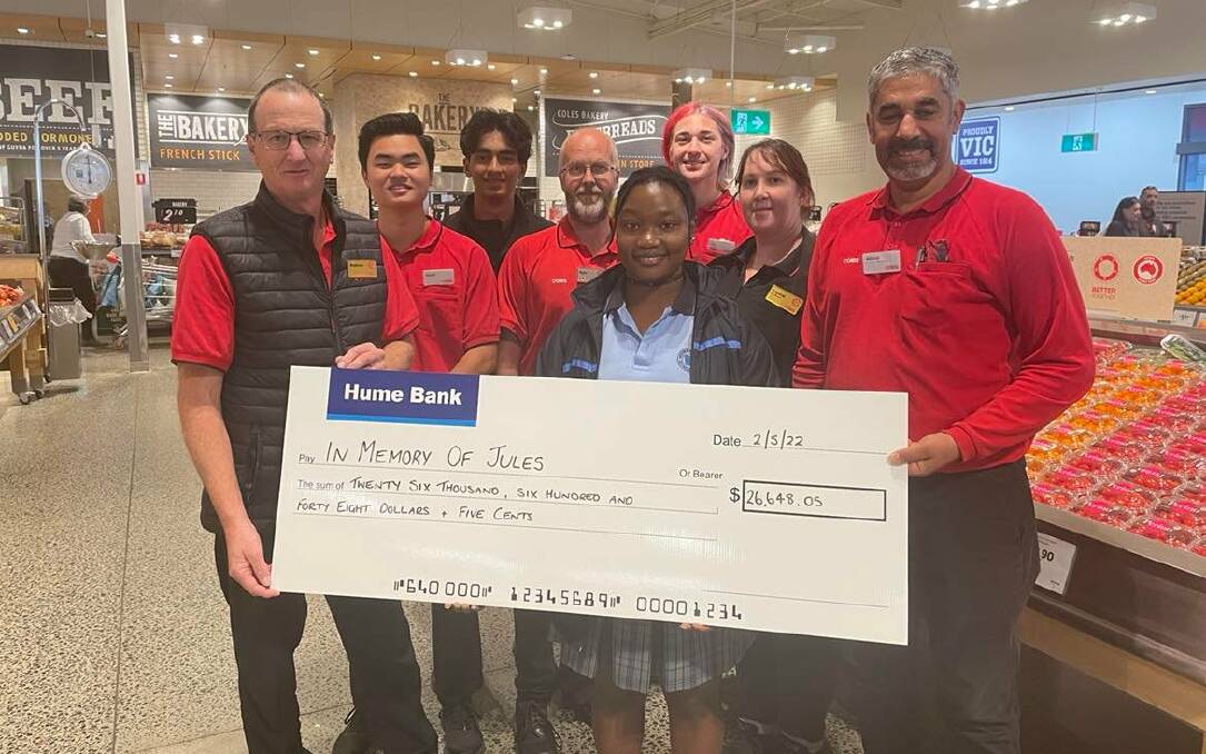 Touching moment: Coles area manager Andrew McGrath (far left) and Coles Services leader Abbas Aleskafi (far right) join other supermarket workers in presenting a cheque to Awezaye Lunanga at the Mann Central store in Wodonga on Monday.