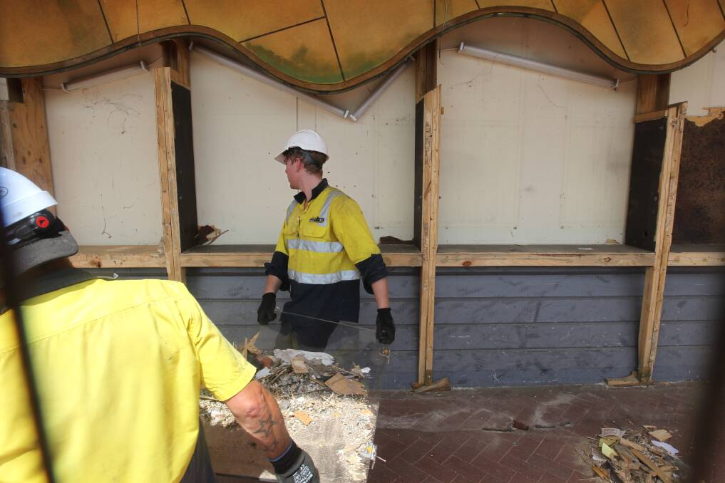 Going, going gone: Workers take away pieces of the mural from High Street on Friday afternoon, exposing the wall of the old Coles supermarket. Picture: BLAIR THOMSON 