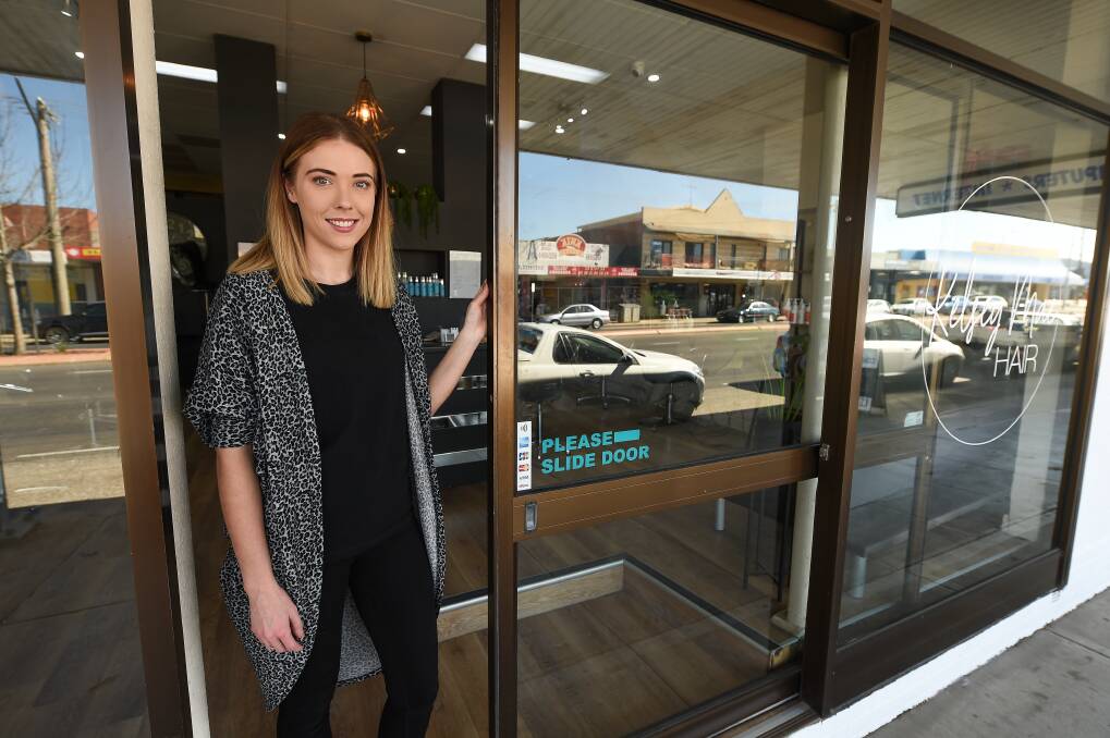 Welcome move: Hairstylist Kelsey Lewington at her Mate Street salon with the front door which had its bottom half damaged by a pedestrian who lashed out with his boot into the glass. Picture: MARK JESSER