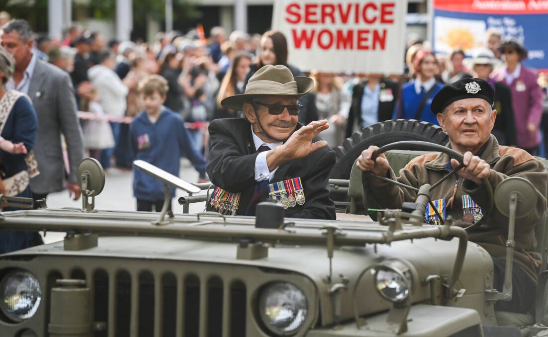 Familiar ritual: Former sapper George Richter, a veteran of the Malayan Emergency, waves to onlookers as he is driven down Dean Street by Barry Wilson who wore the medals of his uncle Steven Wilson who was killed at Gallipoli. Picture: MARK JESSER