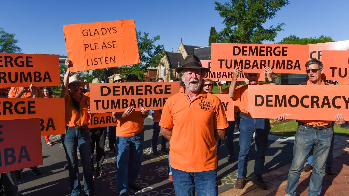 Agents orange: Save Tumbarumba Shire members including Neil Hamilton (front) and Lucy Henderson, who is holding 'Gladys please listen' sign, protest in QEII Square yesterday outside the Local Government NSW Conference. Picture: MARK JESSER 