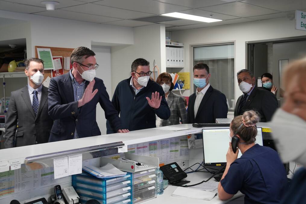 Premiers Dominic Perrottet and Daniel Andrews wave to clerical staff as they tour the Albury hospital with Victorian Health Minister Mary-Anne Thomas, NSW MP Justin Clancy and Albury Wodonga Health board chairman Matt Burke.