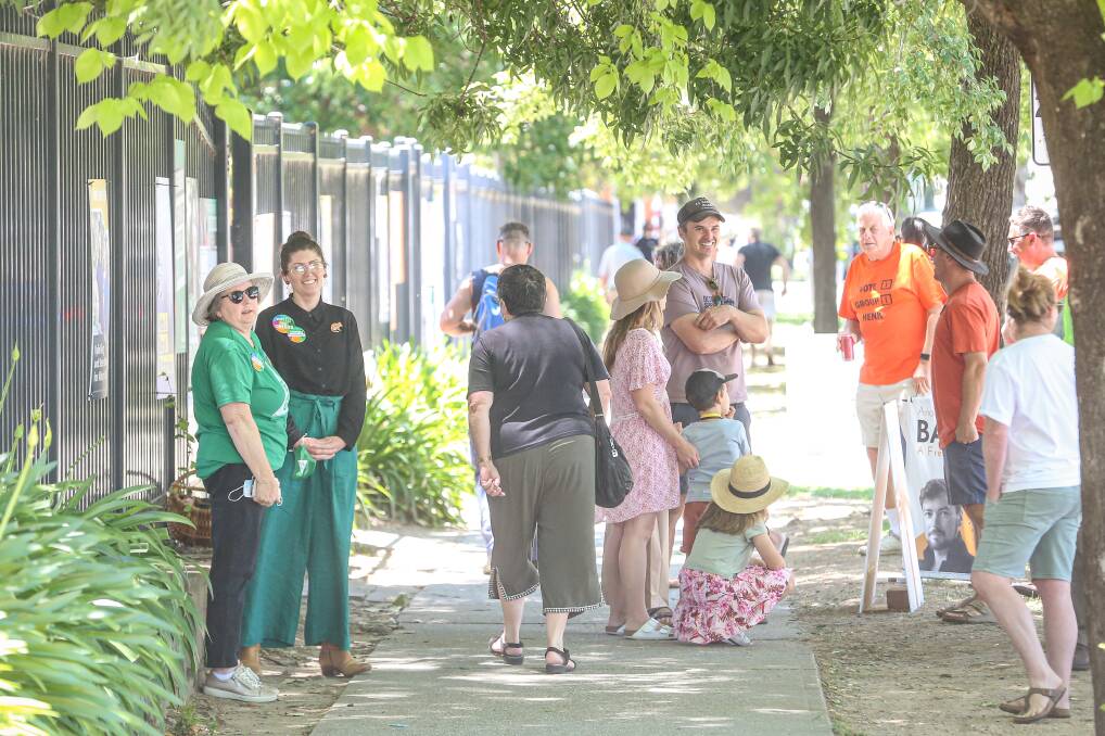 On the hustings: Greens candidate Ashley Edwards (second from left) and councillor Henk van de Ven with can in hand outside the Albury Public School polling booth on Saturday. Picture: JAMES WILTSHIRE 