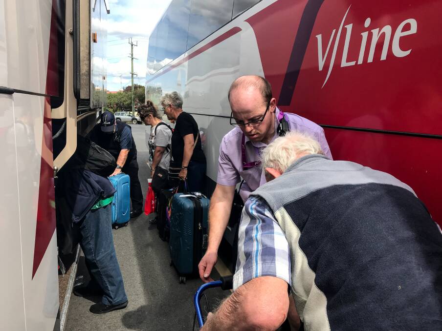 A V/Line representative helps load Peter Vaughan's trolley onto the bus.