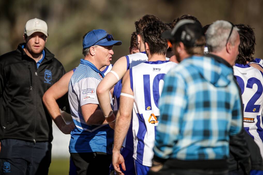 Marc Almond (with blue cap) talks to his playing group during a game last season. He's calling on the league to play games in NSW, if it helps kick-start the season.