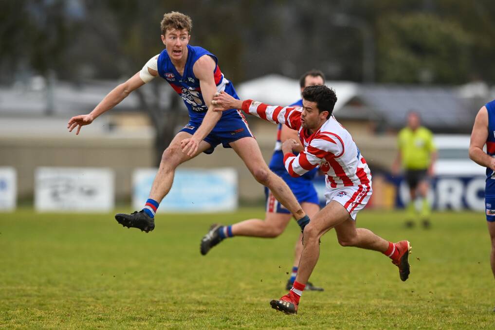 FLYING HIGH: Jindera's Danny Middleton puts everything into his kick downfield as Henty's Liam Sweeney arrives too late. Picture: MARK JESSER
