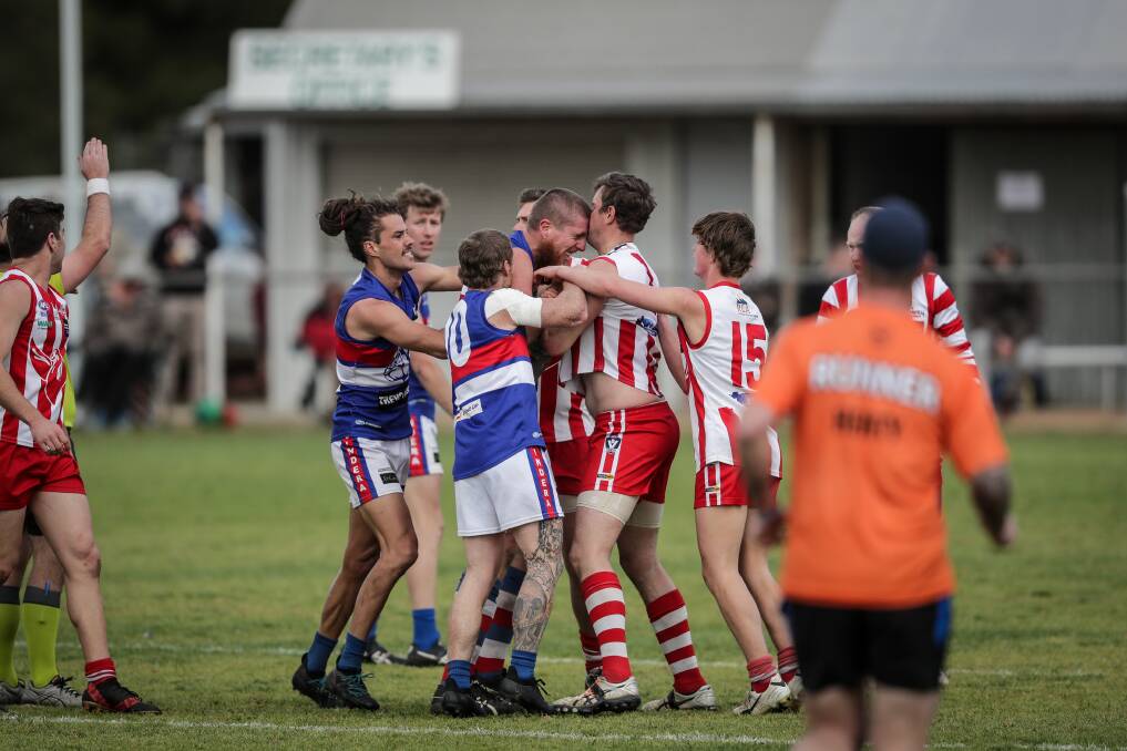 Jindera's Ben Dower comes to grips with Henty's Chris Willis (in the red and white) during the 2018 Hume League finals.