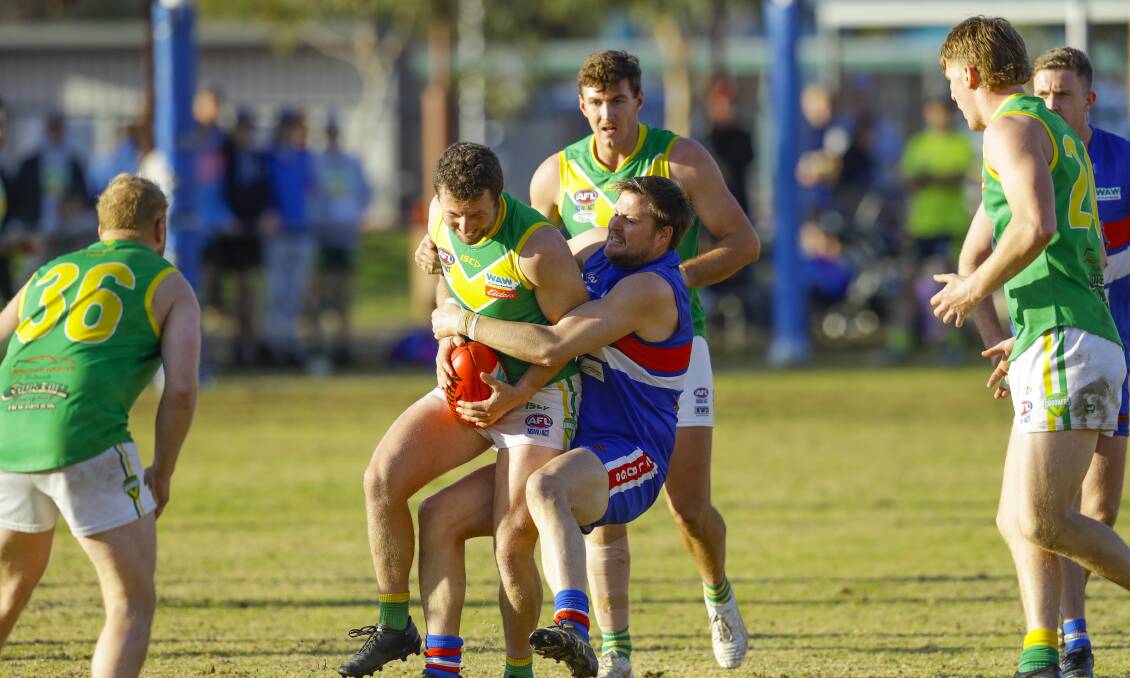 Holbrook assistant coach Andrew Mackinlay is tackled by Bulldogs defender Nathan Chamings.