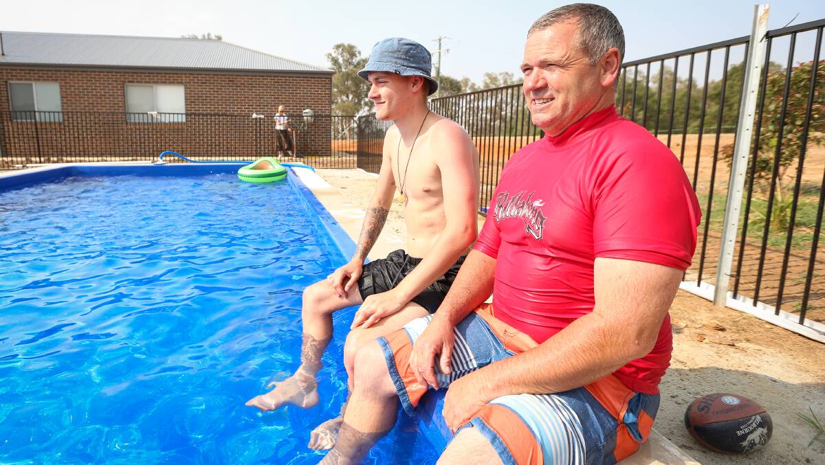 JUST CHILLING: Brodie and Norm Loy relax by the family pool on Wednesday. Picture: JAMES WILTSHIRE