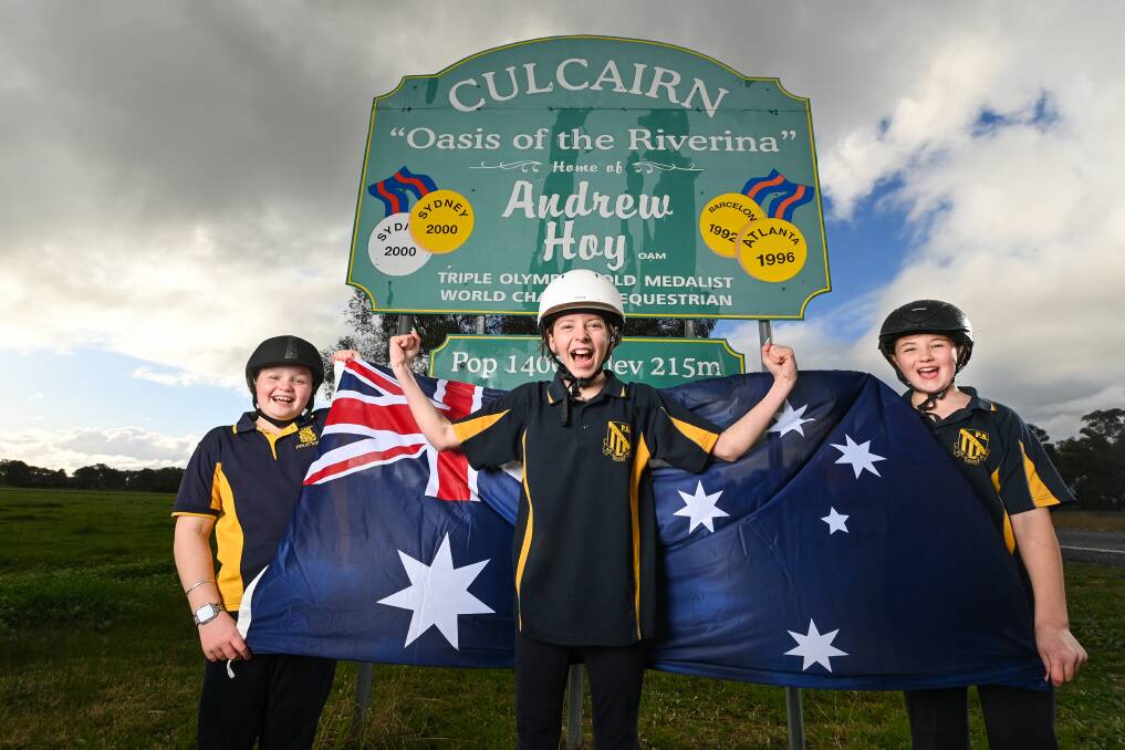 HOMETOWN HERO: Culcairn Public School students Maddison Lloyd 9, Nakoda Navybox, 12 and Annabell Barber, 12, celebrate Andrew Hoy's medal-winning performances at the Tokyo Olympics in front of the entry sign to the Riverina town named in honour of the equestrian champion. Picture: MARK JESSER