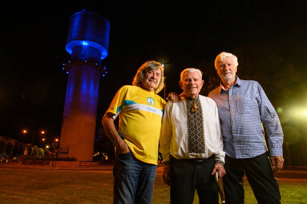 UNITED: Wodonga-based Ukrainians Toli Kolisnyk was 18 months old when his family migrated from Ukraine in 1949 and Joe Wowk was 22. The pair were joined outside Wodonga's Water Tower, which was lit up in support of Ukraine on Sunday night, by former German-Austrian Australian Club president Lutz Peters. Picture: MARK JESSER