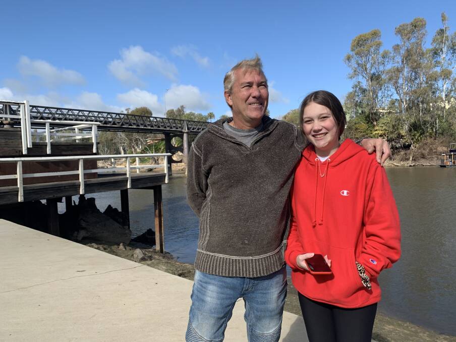 ALL SMILES: Wahgunyah's Brad Plum, with daughter, Tia, 16, enjoying the sunshine in Corowa on Monday. Pedestrian access was granted on John Foord Bridge, but could be taken away with stricter border closure measures to be enforced from midnight Tuesday.