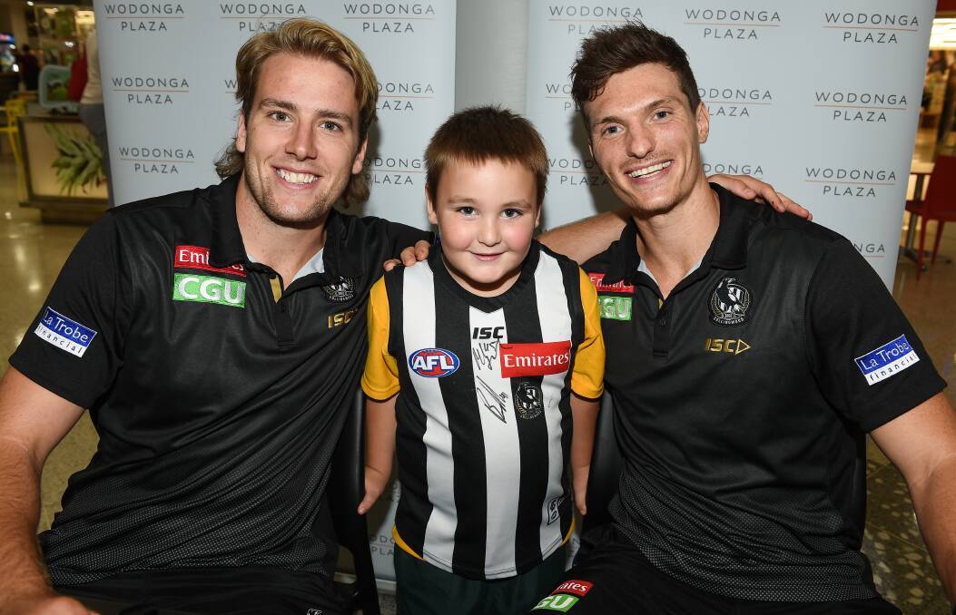 PIE TIME: Collingwood duo Max Lynch and Brody Mihocek with Logan Field, 6, of Wodonga, during the Magpies' visit to the Border as part of the club's community camp on Wednesday. Picture: MARK JESSER