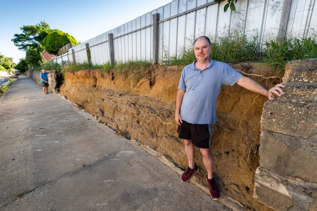 WALL FALLS: North Albury neighbours Ray Dallinger and Colin Reid at either end of the huge stretch of broken retaining wall which lines the storm water drain behind their Wingara Street homes. The pair are concerned another severe storm will cause more damage. Pictures: MARK JESSER