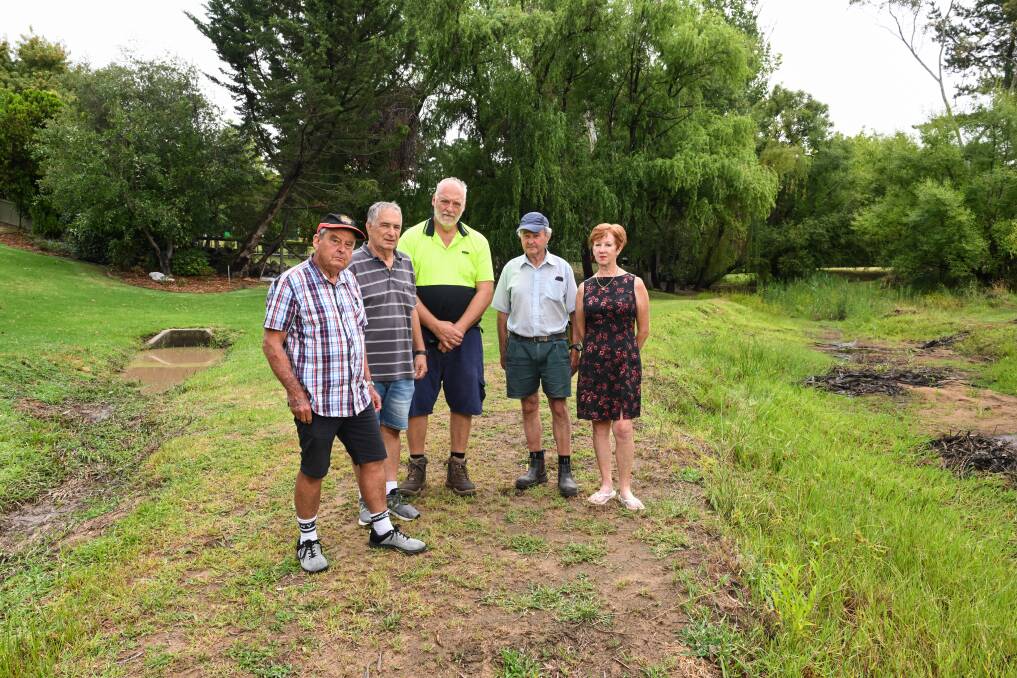 Huon Creek Road residents Ross Black, John Galea, Graeme Ware, Bob Moodie and Margaret Moulton-Ware standing beside the blocked up Huon Creek behind their properties. Picture by Mark Jesser