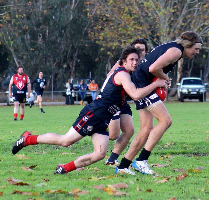 CLINGING ON: Corryong's Thomas Shanks lays a tackle on Cudgewa's Jayden Pryse, but it was the Blues that ran away with a massive win.
