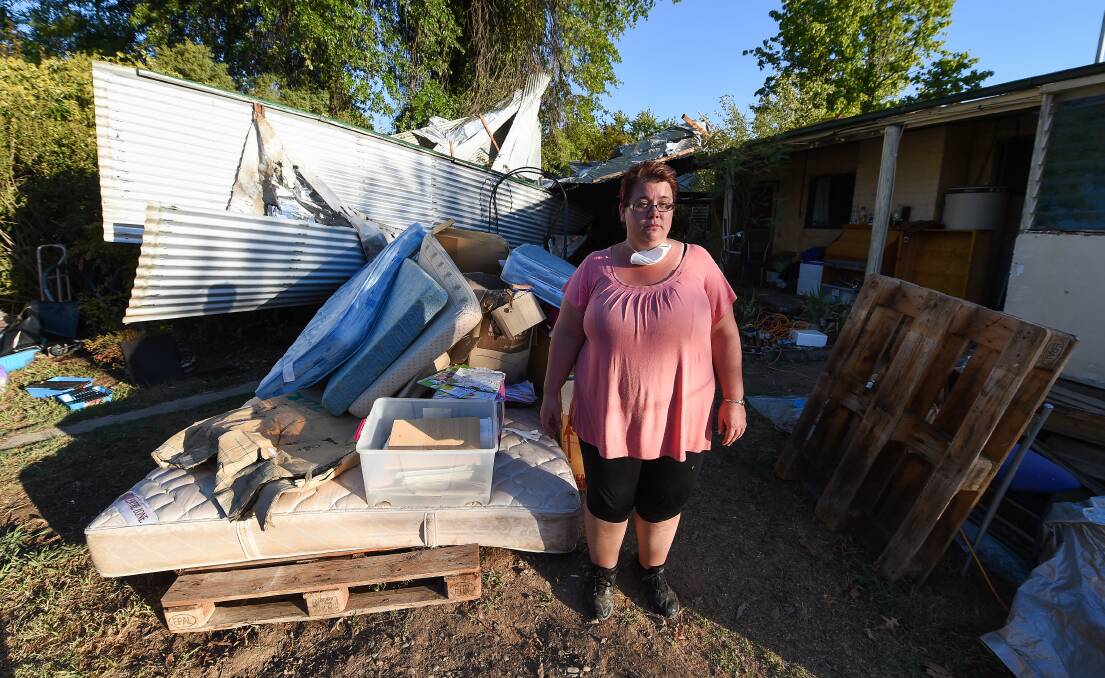 POSSESSIONS: Ms Ardley stands with the roof and some of her family's property destroyed by water. 