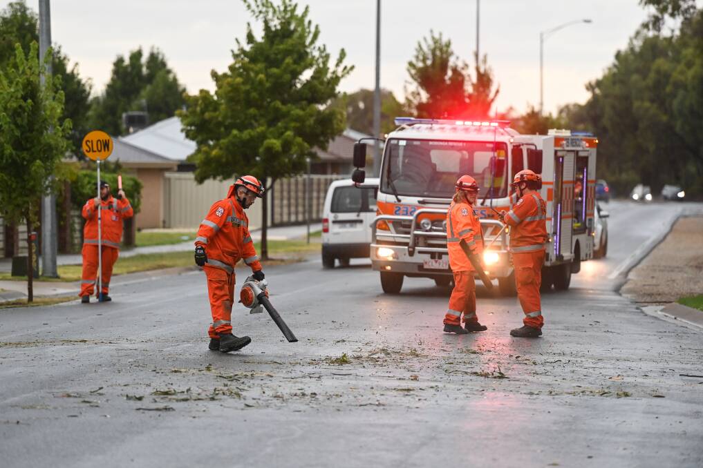 MESS: Wodonga SES members clear debris from Drage Road, Wodonga after a large tree came down yesterday morning. SES in both states are urging people to take precautions with wet and stormy weather to continue until the weekend. Picture: MARK JESSER
