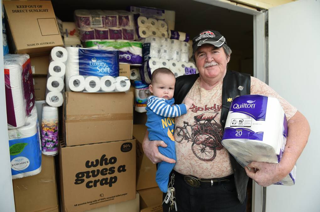 REQUEST: Laurie Reynolds, pictured with his grandson Hayden, 6 months, needs someone to deliver a room-full of sanitary products to Dubbo, where it will go to farmers. He's collected them over eight months. Picture: MARK JESSER 