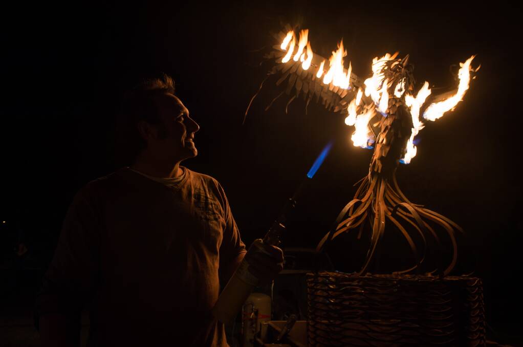 BLAZING: Sculptor Michael Laubli lights up his Phoenix made entirely of re-purposed metal, one of many installations transforming Gateway Village on Thursday night. The free event is being run by Murray Arts. Picture: MARK JESSER