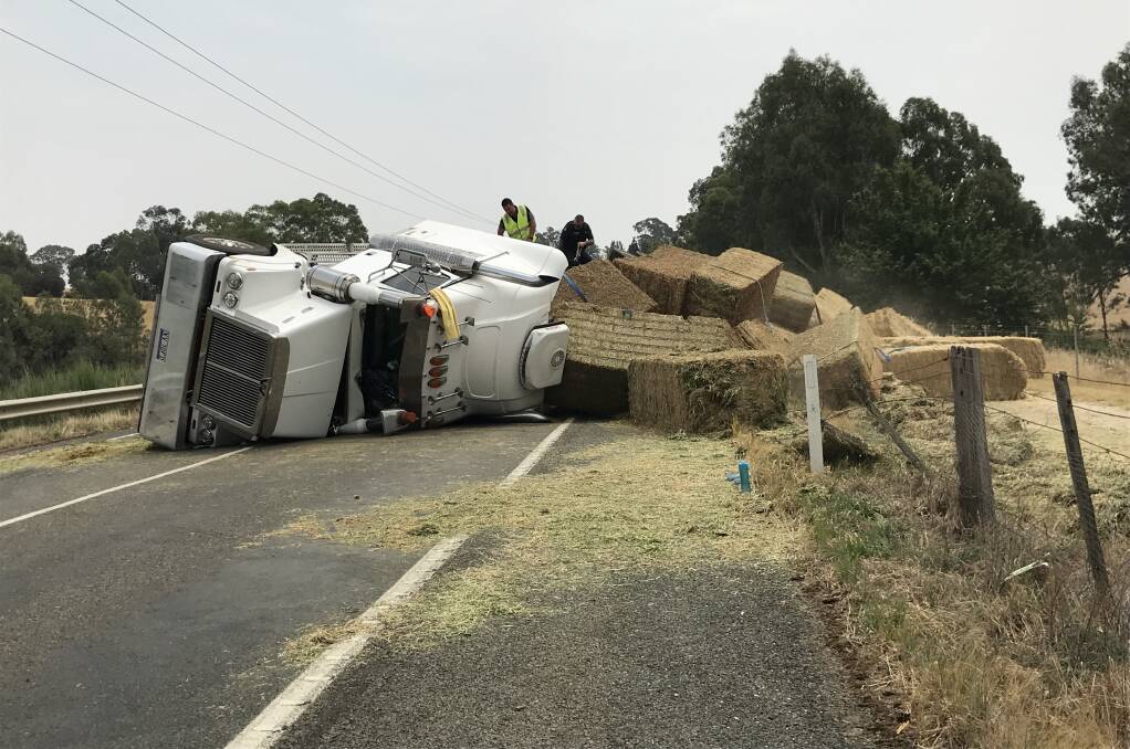 Police and contractors are working to clean up the scene on the Murray Valley Highway west of Tallangatta, where a B-Double transporting hay has rolled. Picture: ELLEN EBSARY