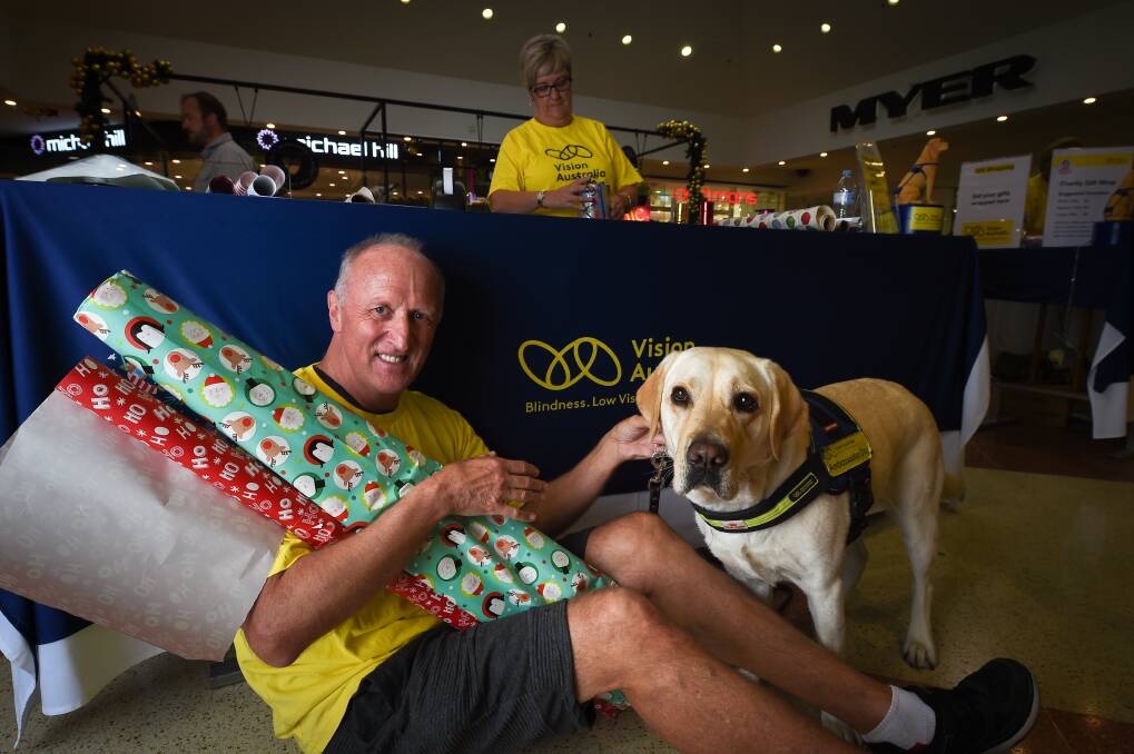 WRAP IT UP: John Atkinson, pictured with seeing eye dog Angela, is one of 30 volunteers wrapping gifts to raise funds for Vision Australia Albury at Myer Centrepoint. Picture: MARK JESSER