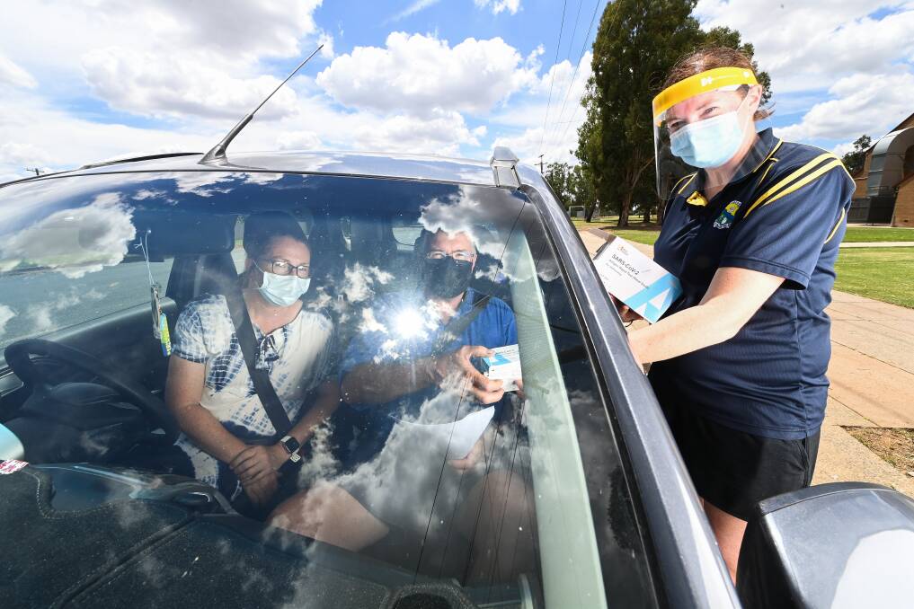 ORDER UP: Parents Toni and Mark Hasler pick up a supply of free rapid antigen tests for their daughter Natalie from Billabong High School's Rachael Hadkins ahead of school going back next week. Picture: MARK JESSER