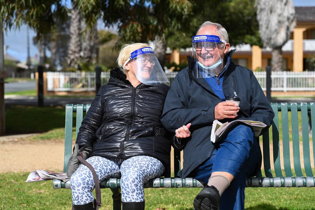 Jill and Eric Barr read the newspaper and have a coffee wearing face shields in Yarrawonga in August. From 11.59 on October 11, face shields will no longer be allowed in Victoria - a fitted mask is required.